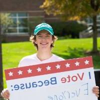 Student holding sign titled "I vote because: Everyone should"